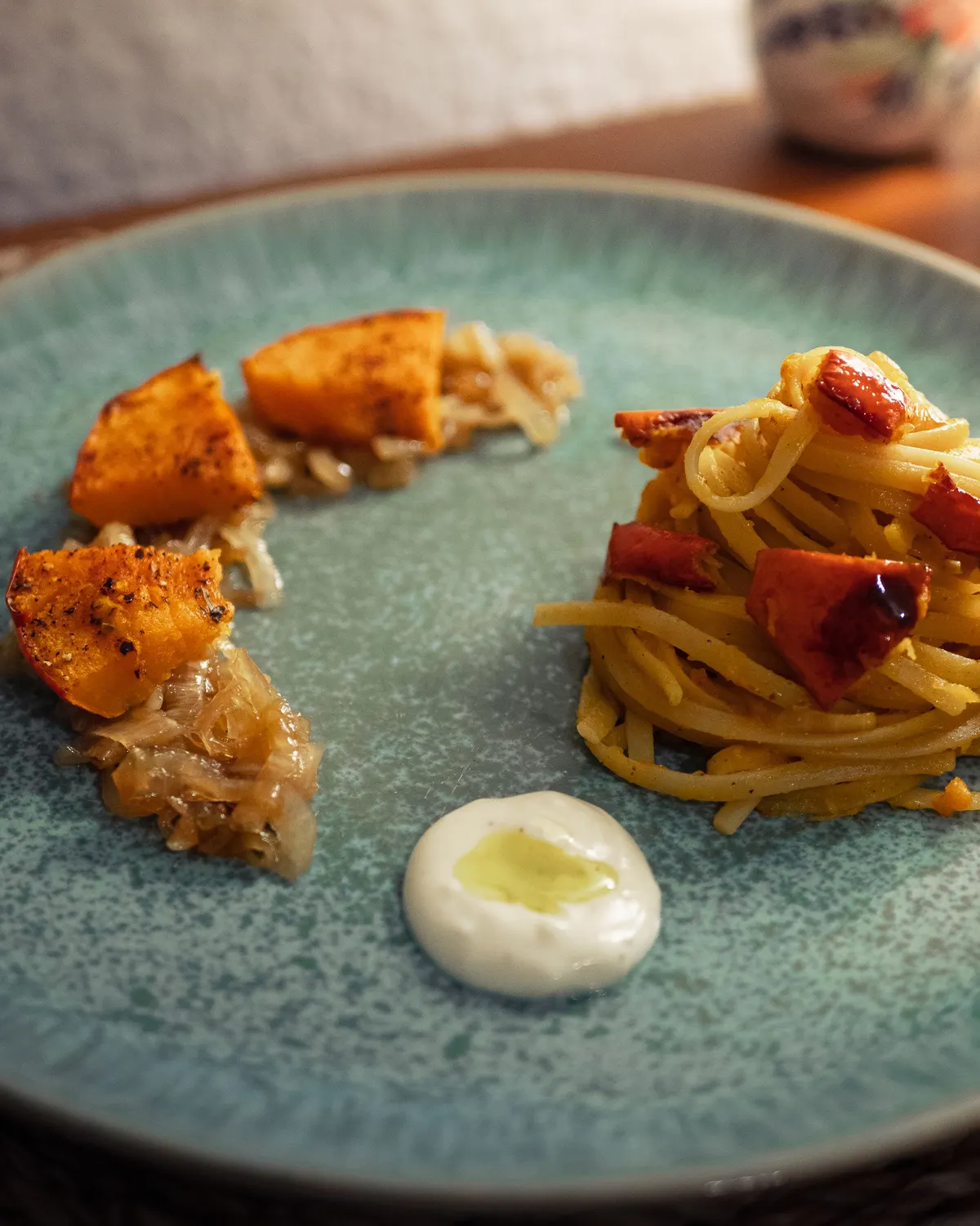 Assiette de saison : courge rôtie, oignons confits et spaghetti, sur une assiette en grès vert