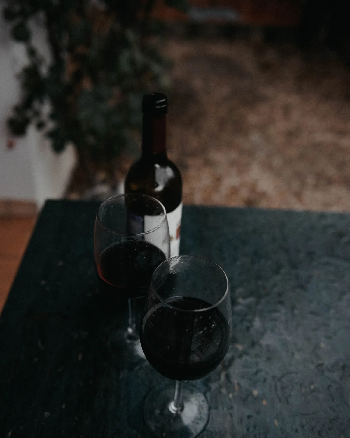 Une bouteille de vin rouge et deux verres servis sur une table sombre
