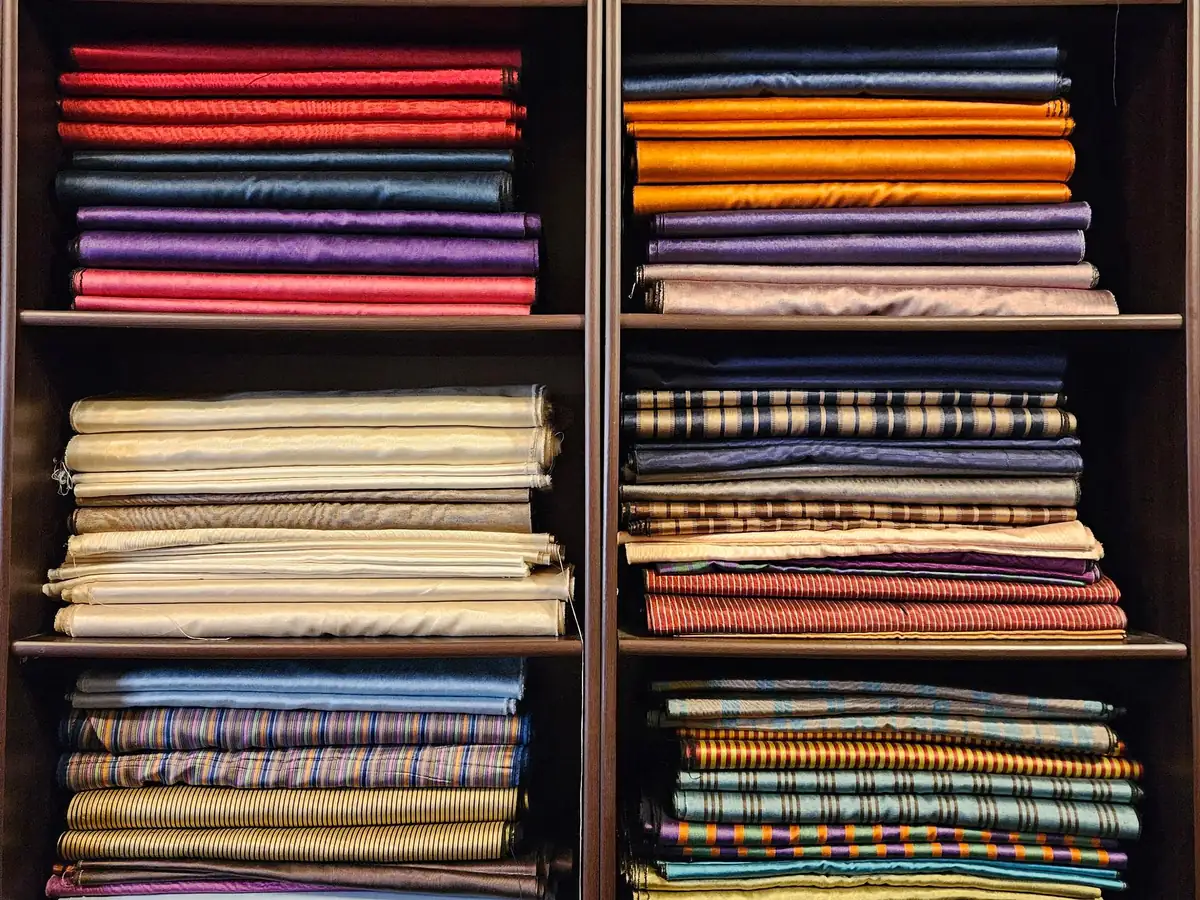Étagères en bois remplies de tissus pliés de toutes les couleurs, unis, rayés et à carreaux