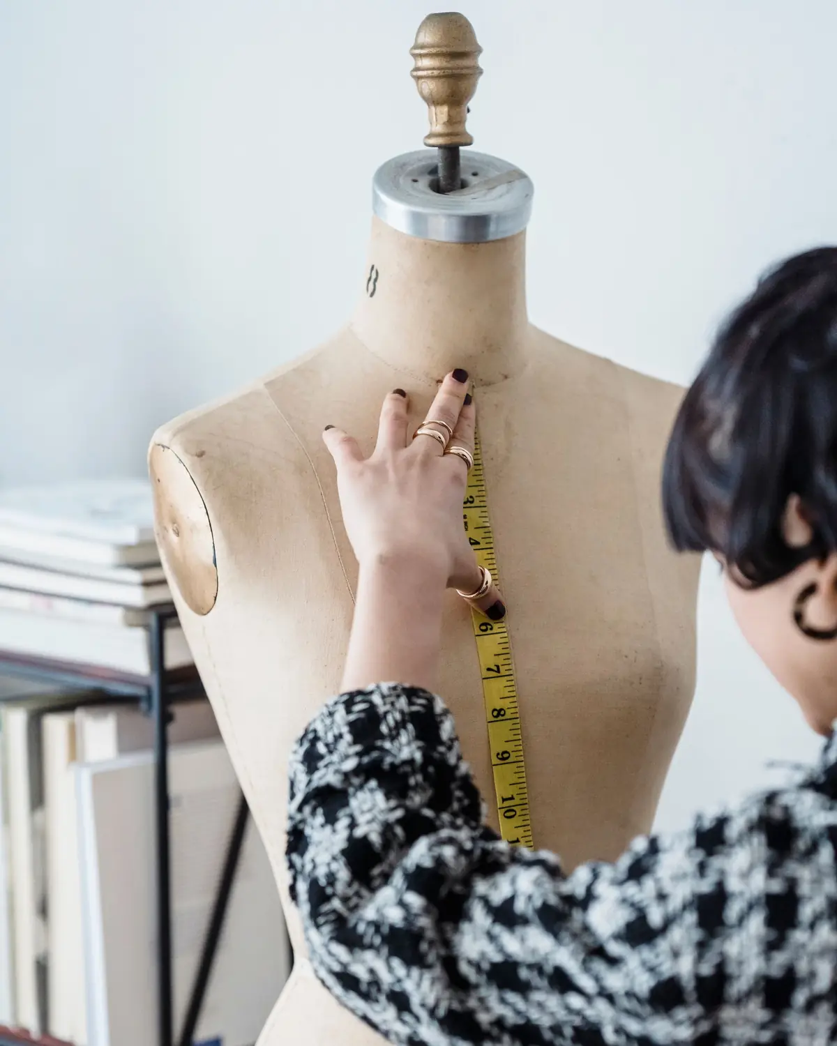Une couturière prend des mesures au mètre ruban sur un mannequin de couture