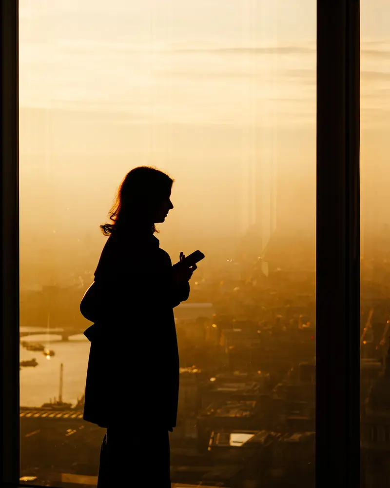 Claire : silhouette d'une femme au téléphone devant une baie vitrée (photo d'illustration)