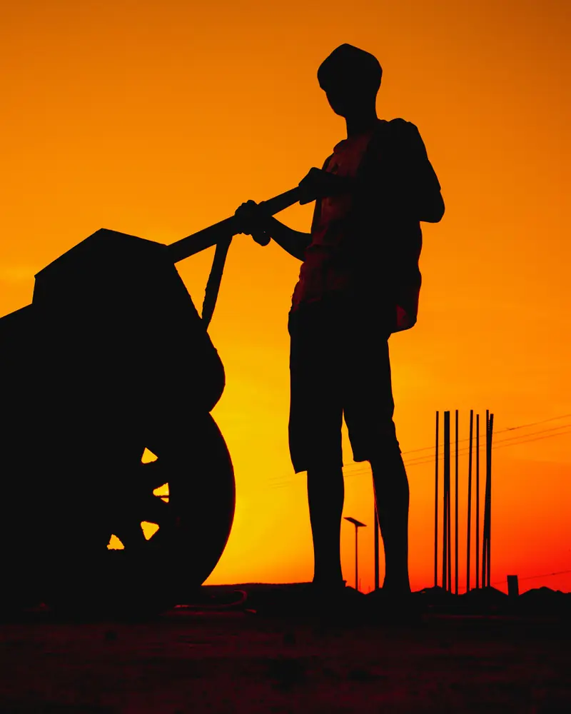 Lucas : silhouette d'un jeune ouvrier poussant une brouette au coucher du soleil (photo d'illustration)