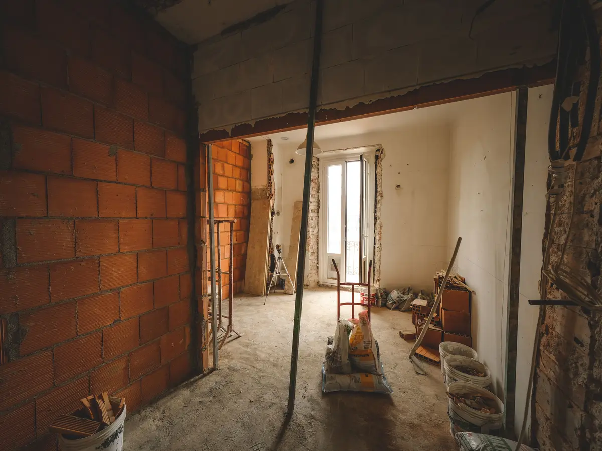 Large ouverture créée entre deux pièces en rénovation, soutenue par des étais métalliques