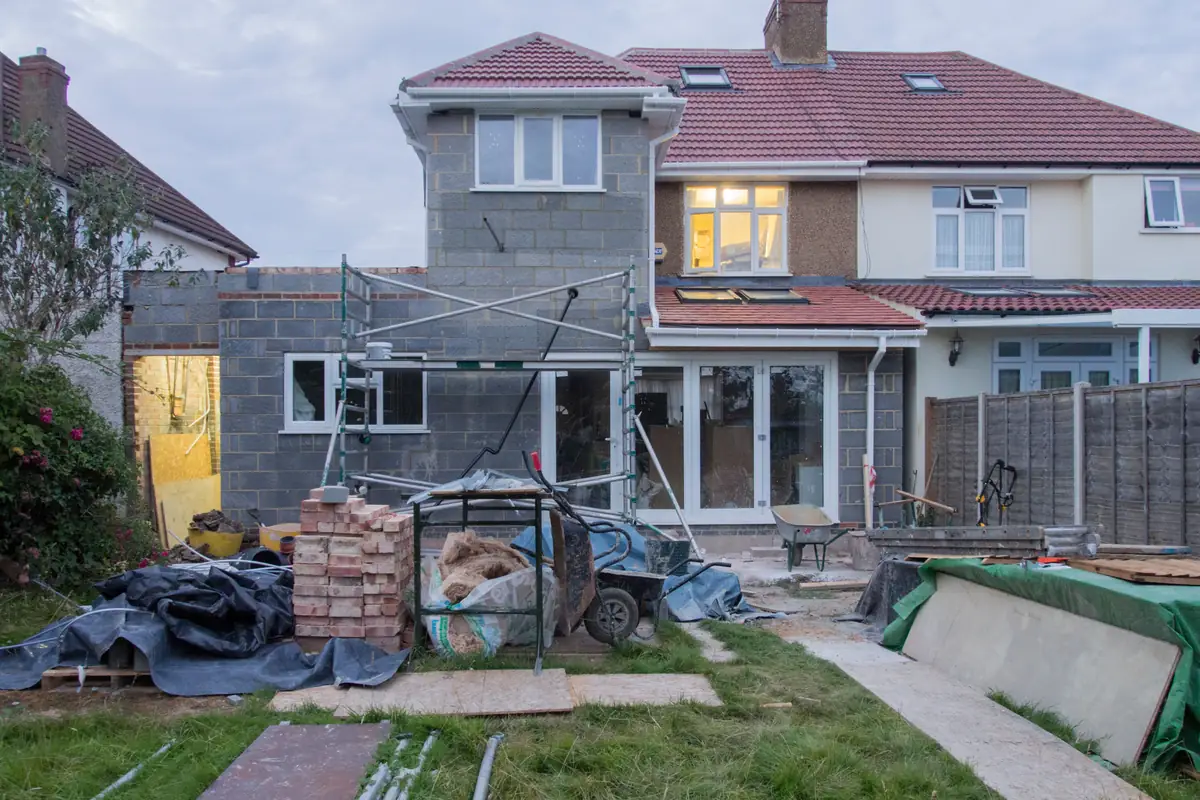 Extension de plain-pied en parpaings à l'arrière d'une maison, échafaudage et matériaux dans le jardin